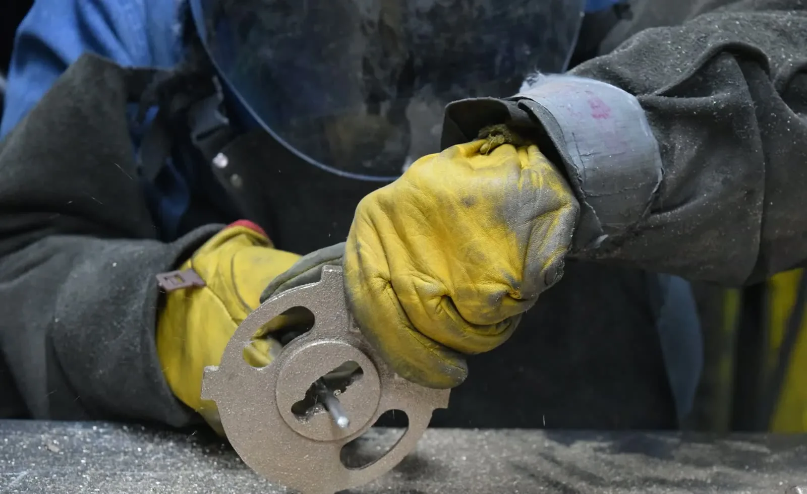 Gloved hands inspecting the finished surface of a steel casting